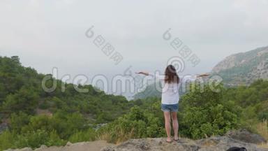 年轻女子站在山顶上举手